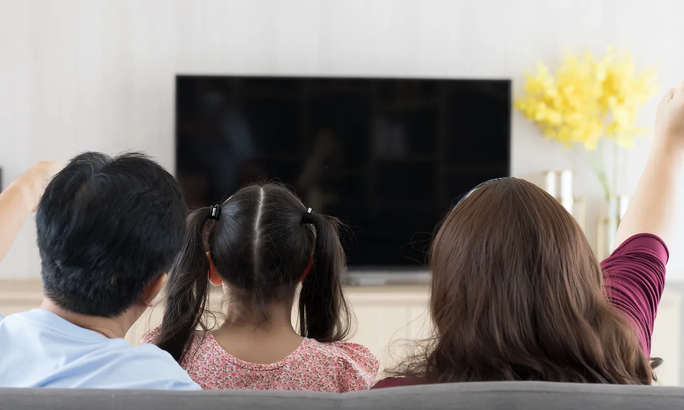 A family on the sofa, seen from behind, watching their TV.