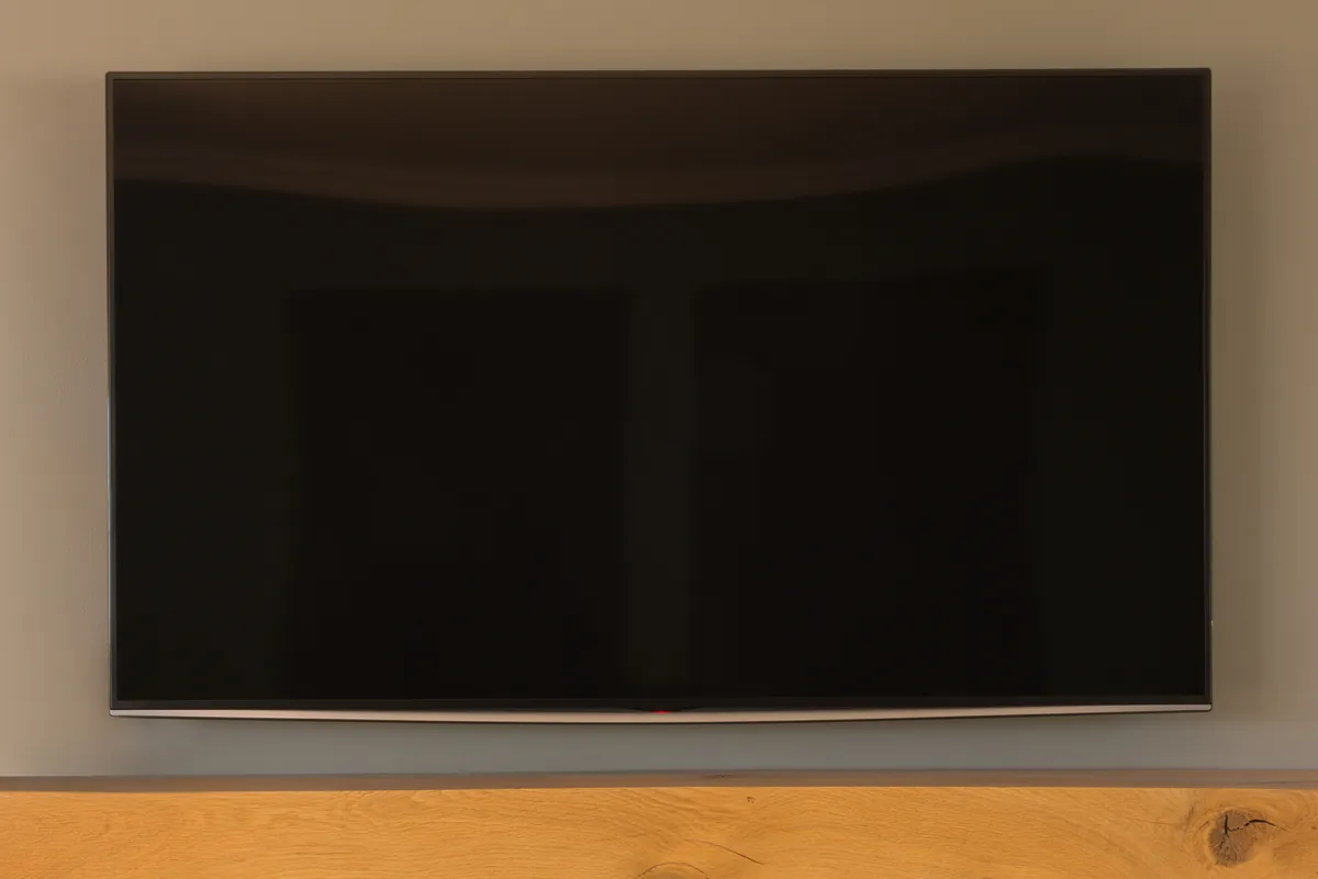 A TV on the living-room wall above a wooden mantel, showing FamilyOrganization.app.